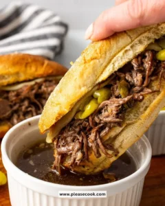 Crockpot Italian beef sandwiches served on buns with peppers and au jus.