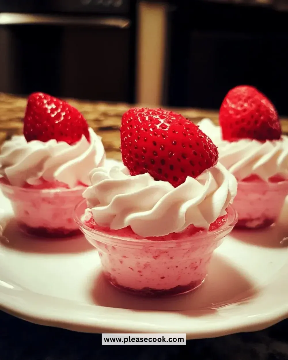 Fluffy strawberry mousse cups topped with fresh strawberries and mint leaves