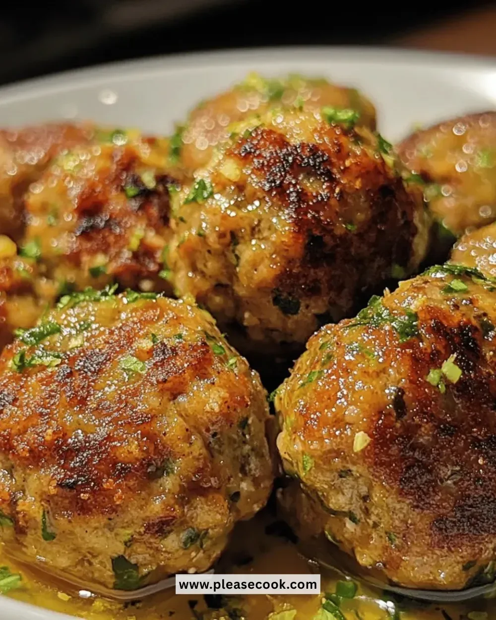 Savory roasted turkey meatballs served on a plate with herbs.