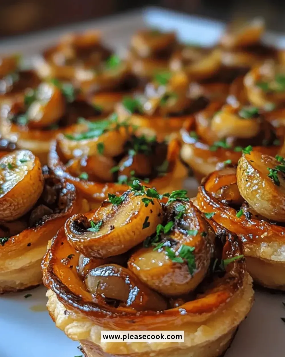 Mini mushroom tart bites topped with fresh herbs and served on a wooden platter.