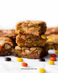Homemade Peanut Butter Blondies on a wooden table with chocolate drizzle