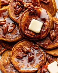Delicious pumpkin pancakes served on a plate with whipped cream and syrup