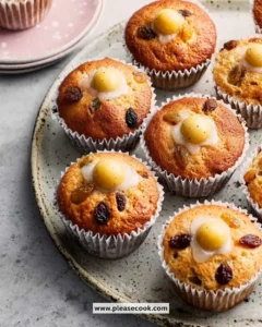 Close-up of freshly baked Simnel Muffins garnished with marzipan and dried fruits.