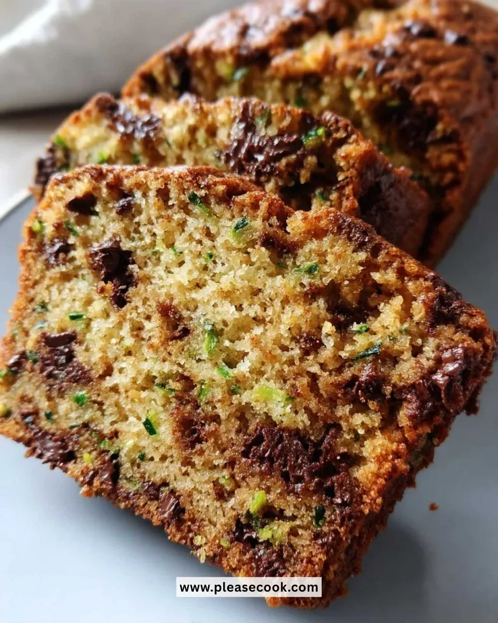 Slice of moist chocolate chip zucchini bread on a wooden cutting board