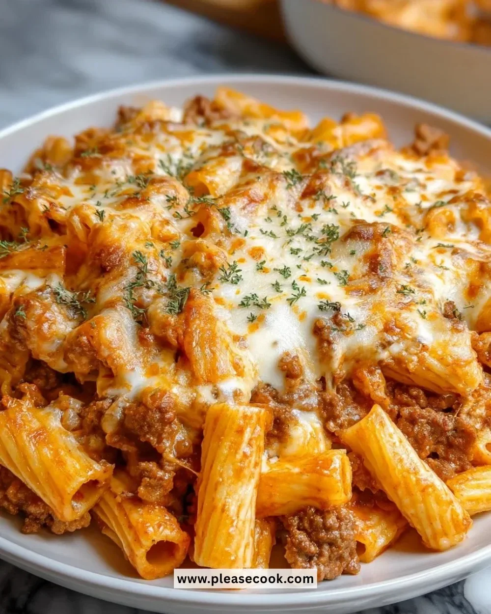 Creamy Beef Rigatoni Cheese Bake topped with melted cheese and herbs.