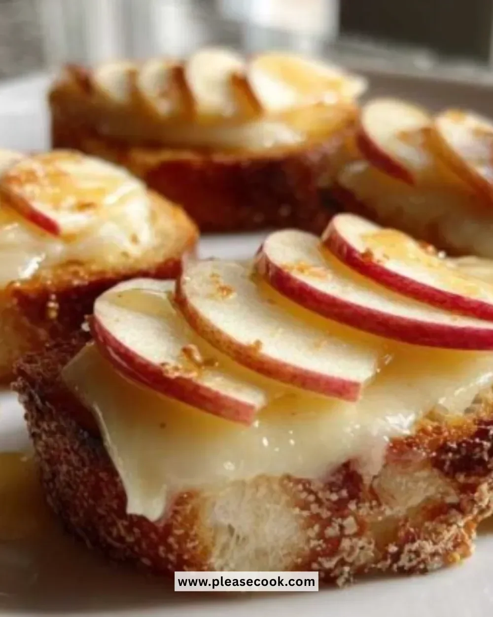 Brie Apple Crostini topped with fresh apple slices and herbs on a wooden board.