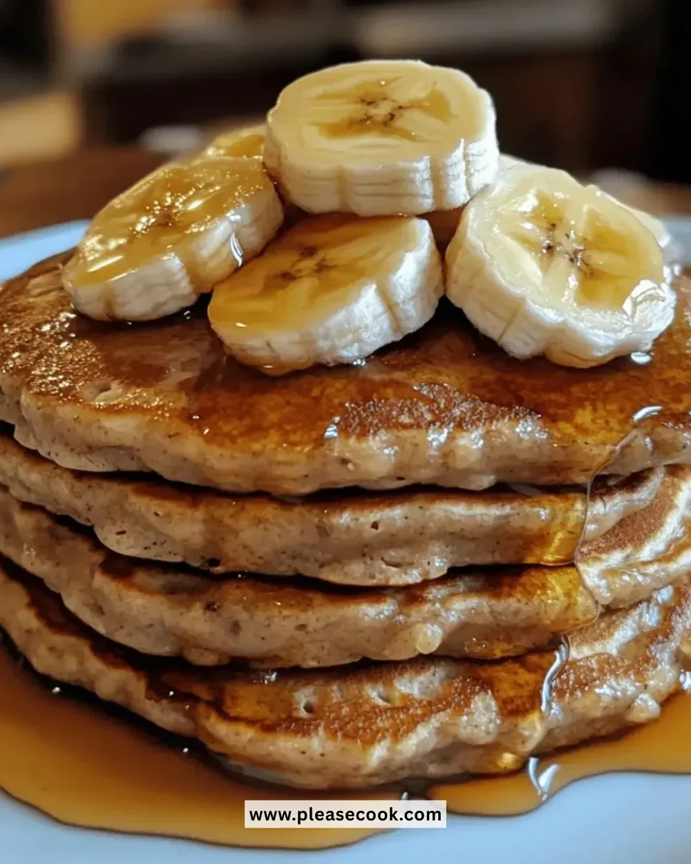 Fluffy banana oat pancakes stacked on a plate with syrup and fruit