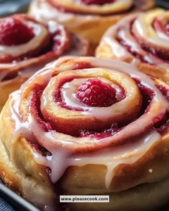 Freshly baked raspberry cinnamon rolls drizzled with icing and raspberries