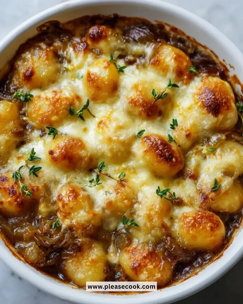 Baked French onion gnocchi topped with melted cheese and herbs