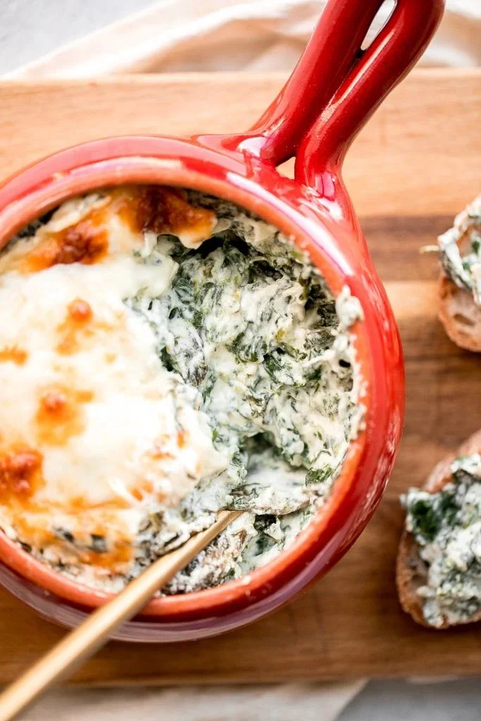 Baked spinach dip served in a rustic dish with crackers on the side
