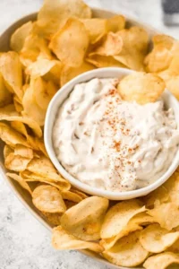 Creamy caramelized onion dip in a bowl served with crispy chips