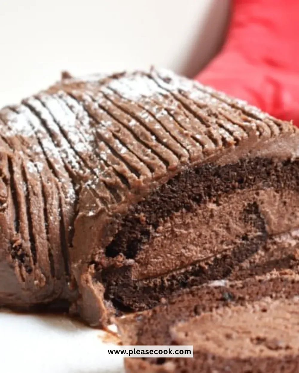 Slice of Chocolate Yule Log Cheesecake topped with chocolate shavings on a festive plate