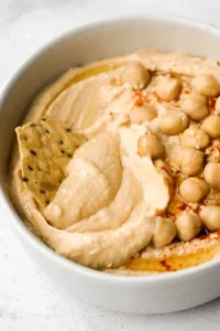Bowl of classic hummus with olive oil and herbs