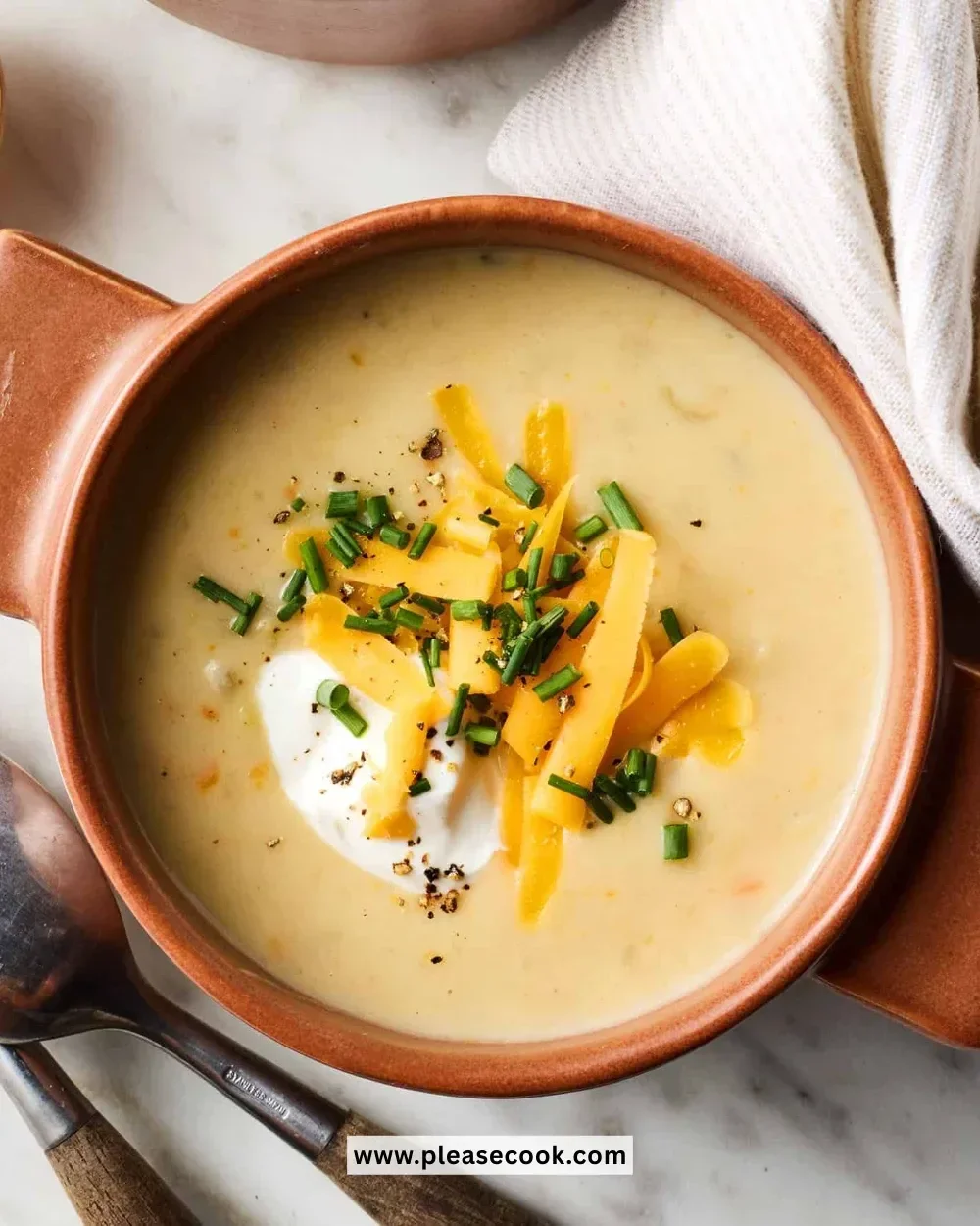 Bowl of creamy potato soup topped with fresh herbs and crispy bacon
