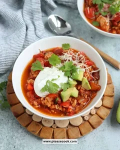 Bowl of ground chicken chili garnished with herbs