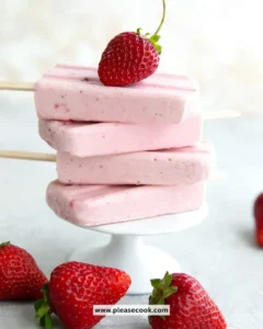 Keto strawberry cheesecake popsicles served on a wooden stick with fresh strawberries