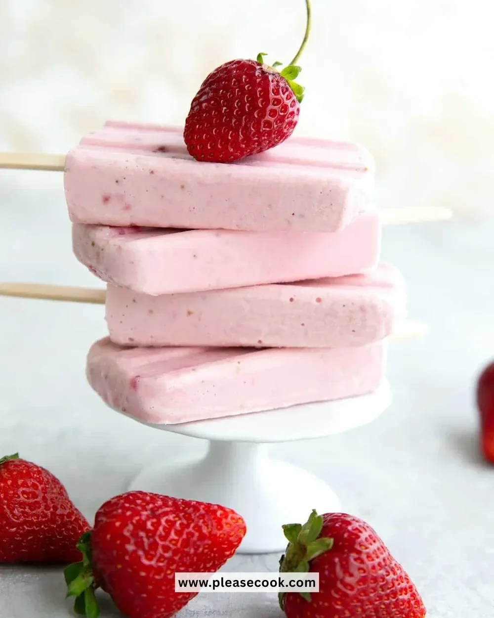 Keto strawberry cheesecake popsicles served on a wooden stick with fresh strawberries