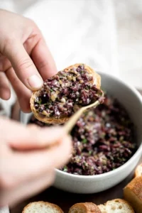 Delicious homemade olive tapenade served in a bowl with bread slices