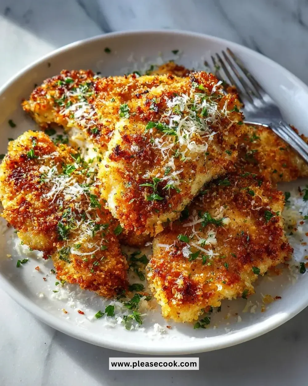 Plate of crispy Parmesan Garlic Chicken garnished with herbs and served with vegetables