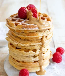 Delicious protein waffles drizzled with syrup and topped with fresh berries