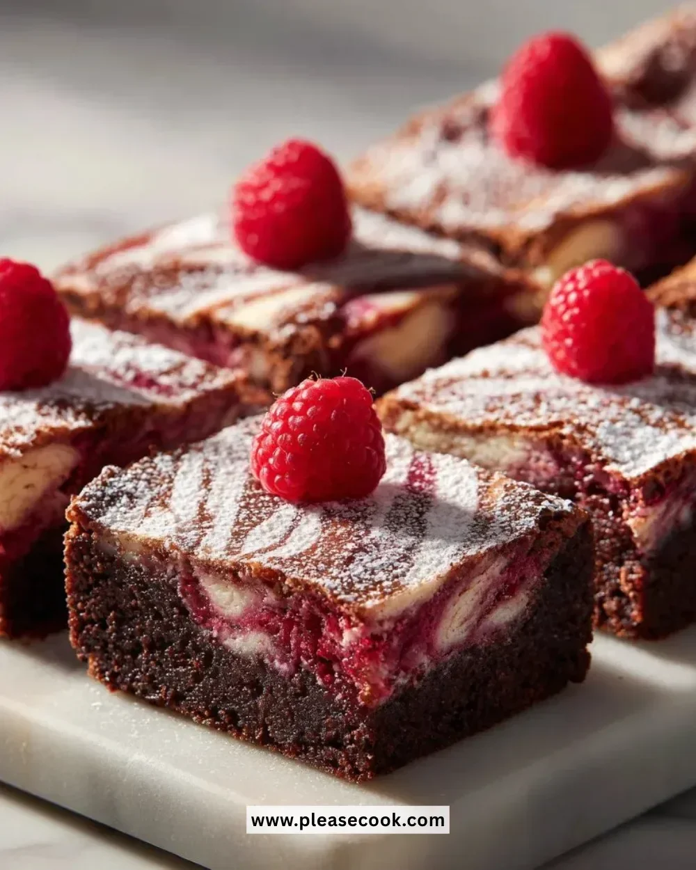 Delicious raspberry brownies topped with fresh raspberries on a white plate