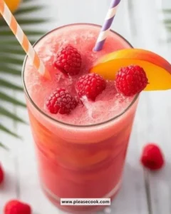 Refreshing Raspberry Peach Ginger Slushie in a glass with ice and fruit garnishes.