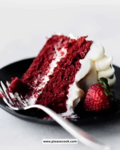 A slice of red velvet cake with cream cheese frosting on a white plate