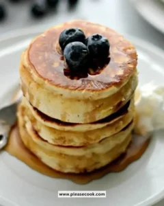 A stack of delicious Scottish pancakes served with syrup and fresh berries.