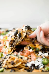 Delicious sheet pan nachos topped with cheese, jalapeños, and guacamole.