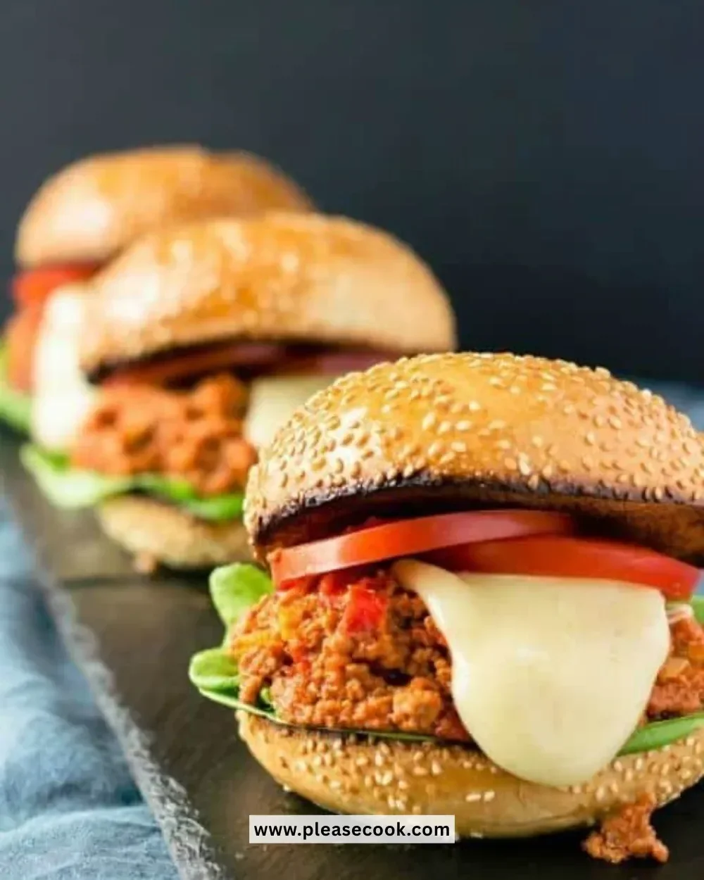 Plate of juicy Sloppy Joes burgers with toppings on a wooden table.
