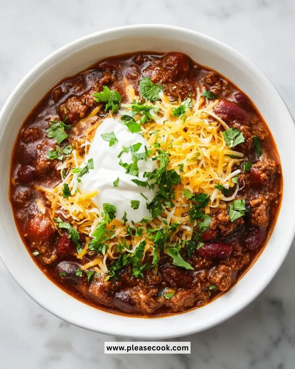 A bowl of ultimate beef chili topped with cheese and fresh herbs