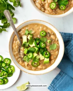 Bowl of creamy white bean soup garnished with herbs and croutons