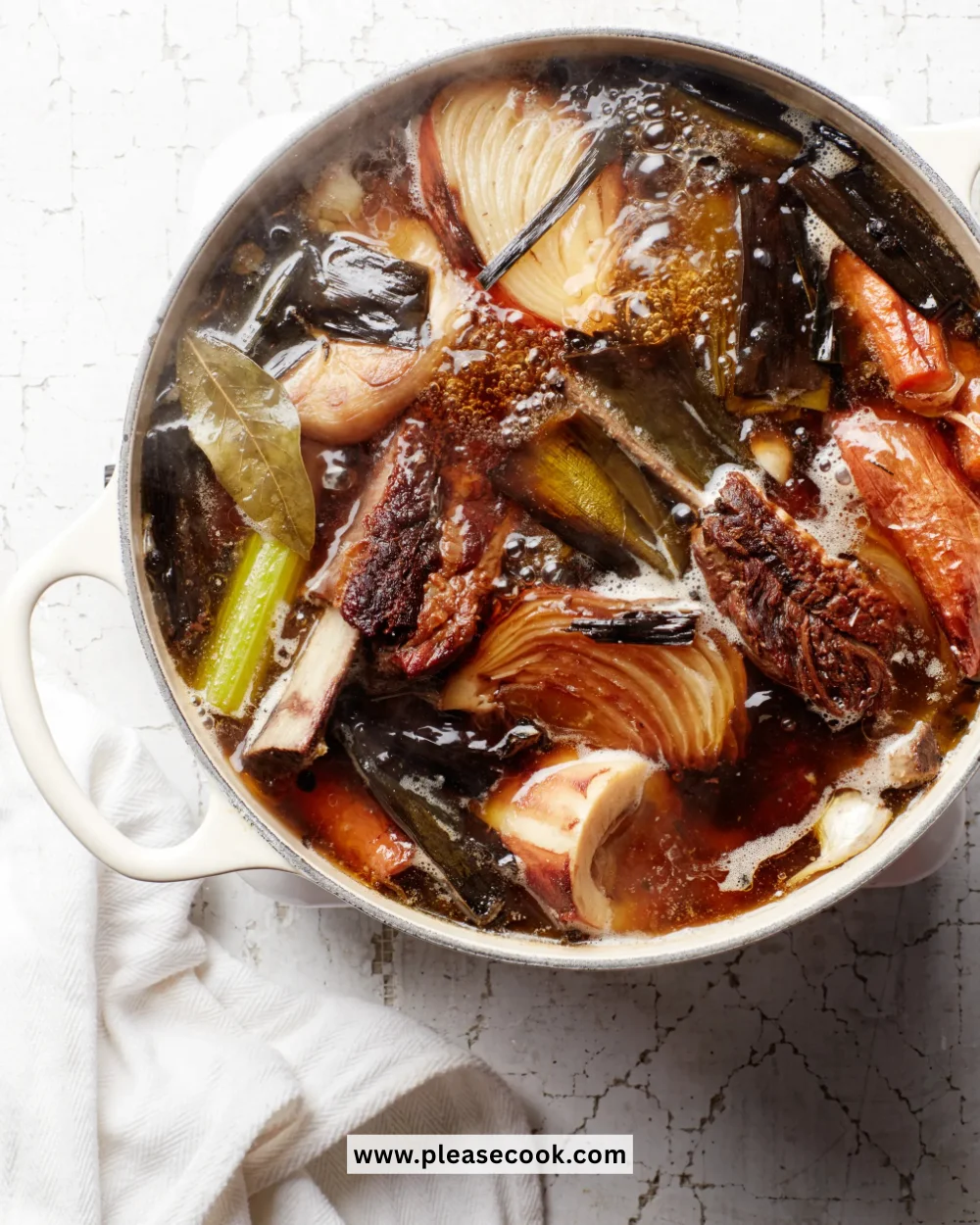 Homemade bone broth simmering in a pot with fresh ingredients
