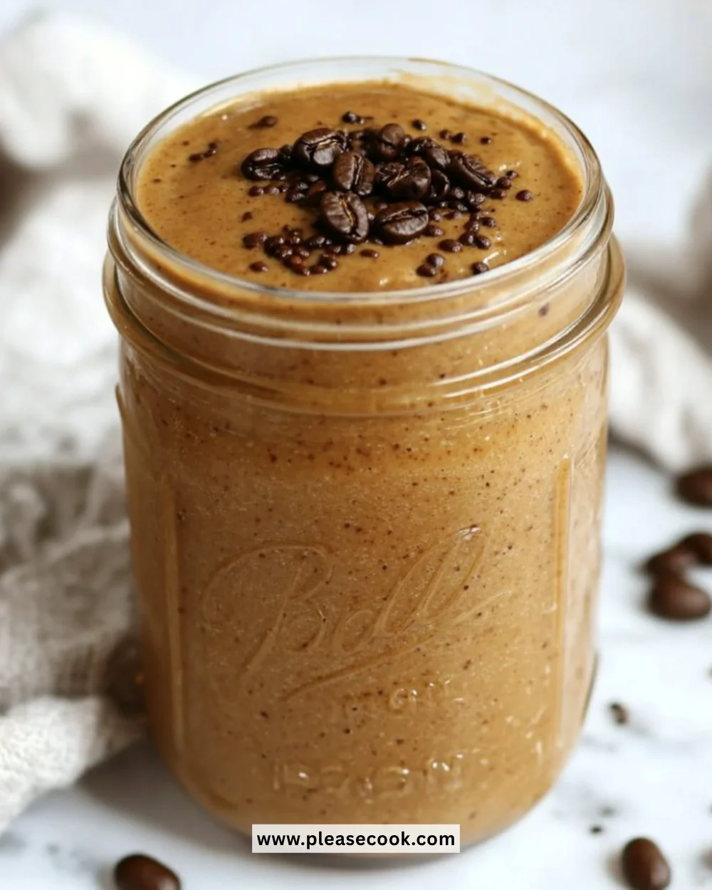 A delicious coffee smoothie in a glass topped with whipped cream and cocoa powder.