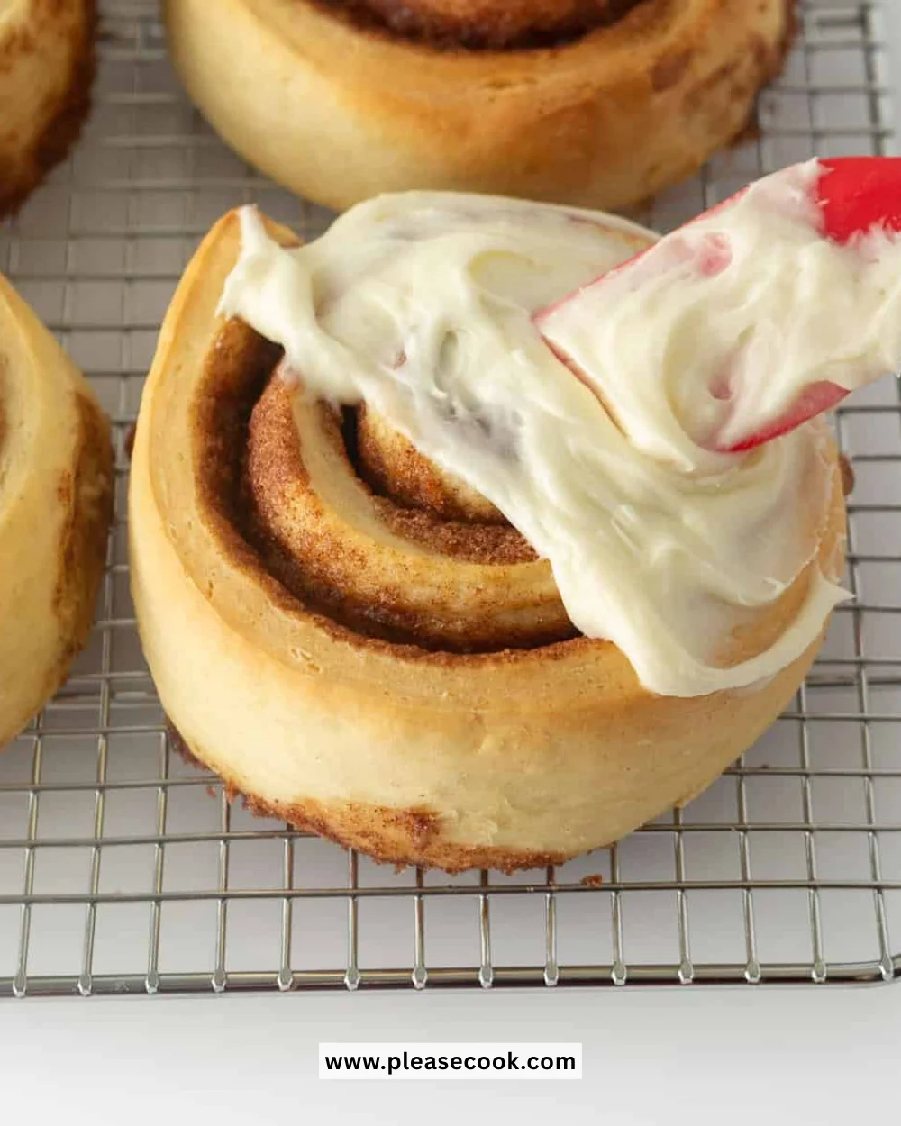 Cream cheese frosting spread on warm cinnamon rolls