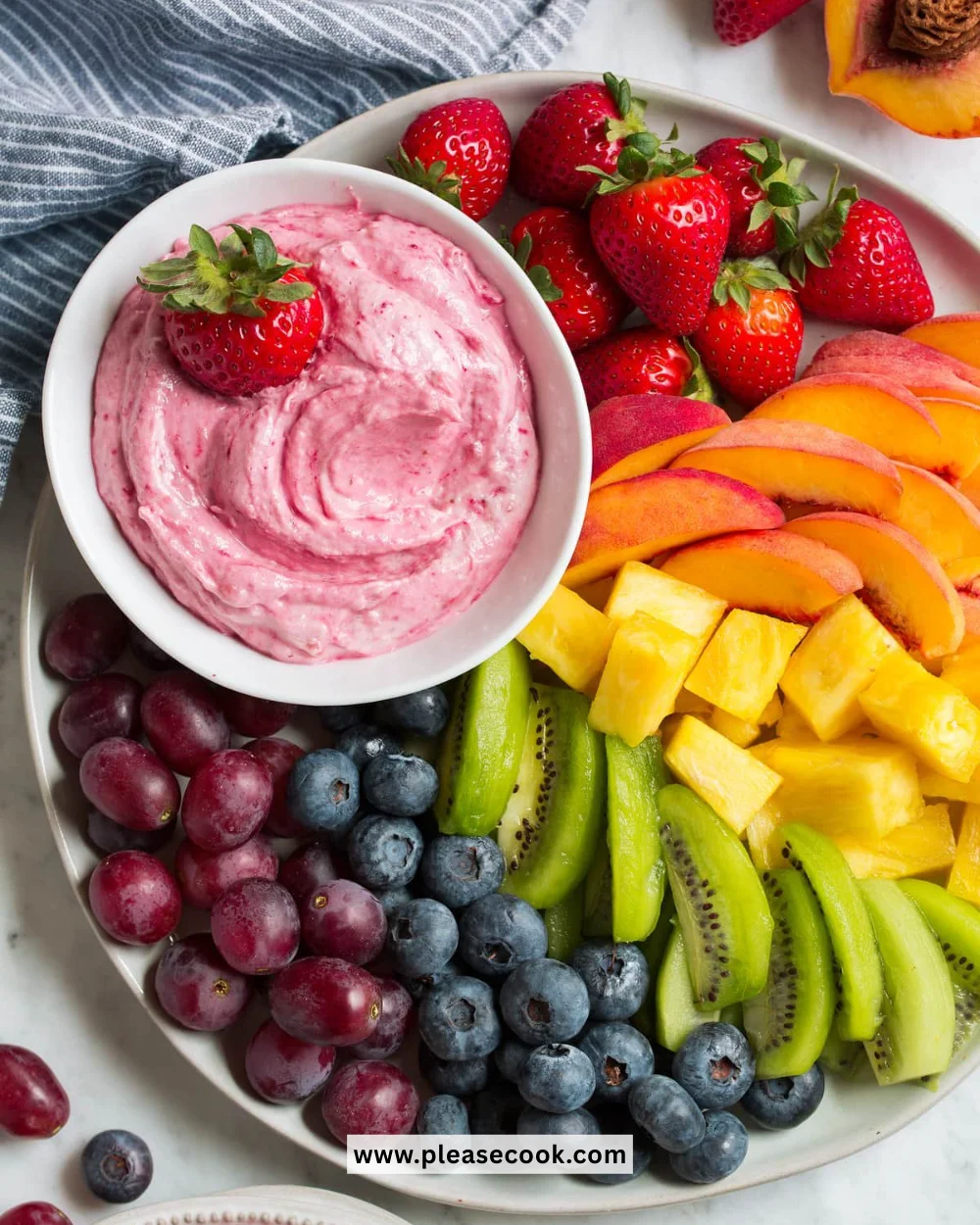 A colorful spread of fresh fruits with a creamy fruit dip in a bowl