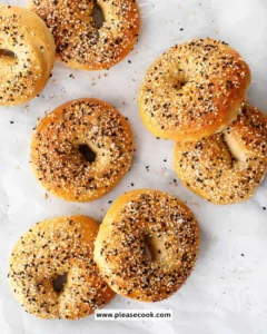 Freshly baked homemade bagels with sesame seeds on a wooden board.