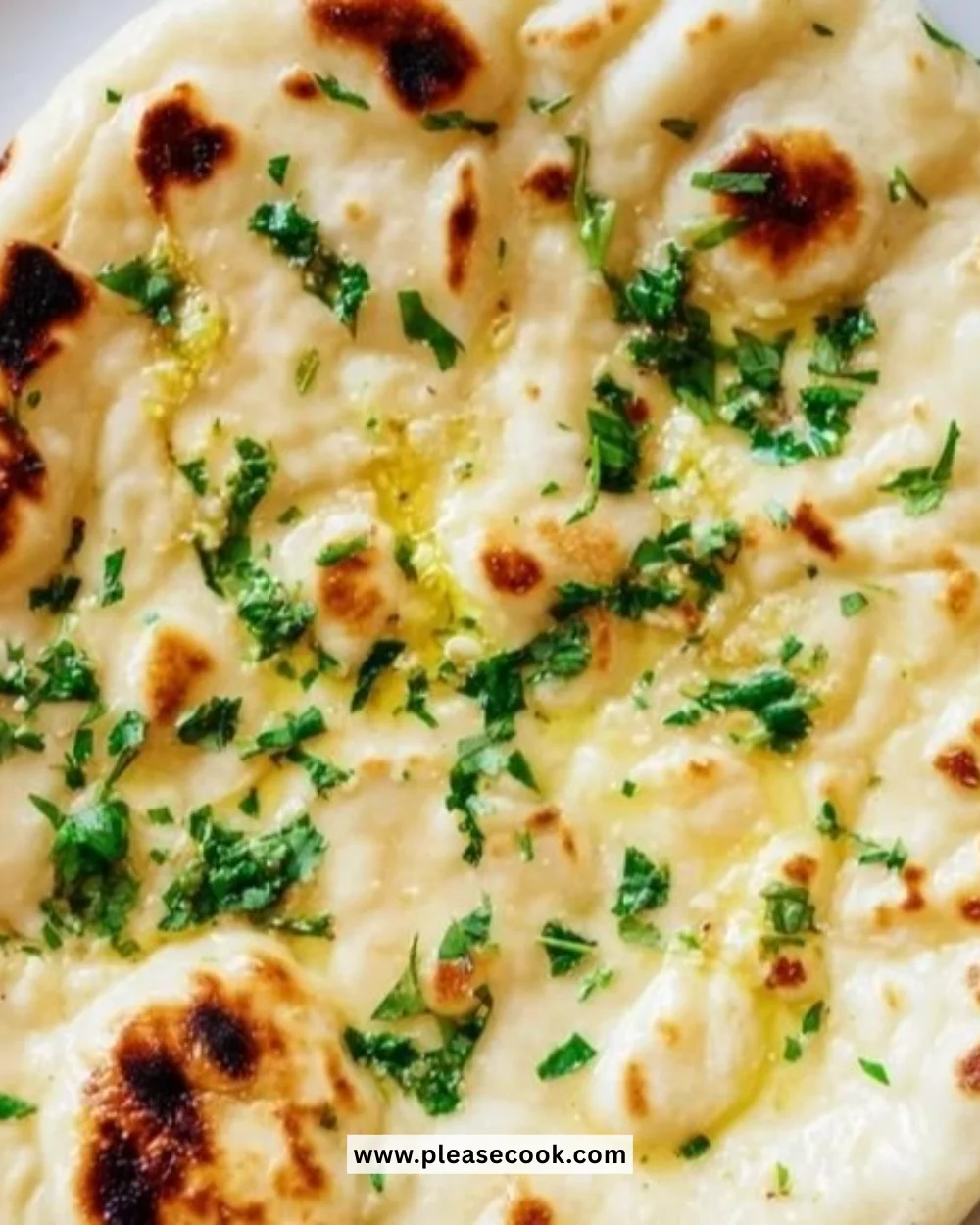 Freshly baked homemade garlic naan bread on a wooden surface.