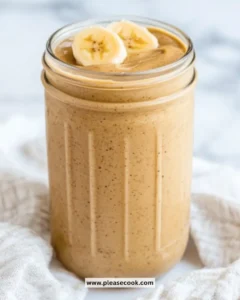 Creamy Peanut Butter Banana Smoothie in a glass with banana slices and a spoon