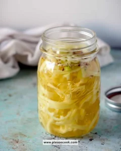 Homemade pickled banana peppers in a jar with spices.