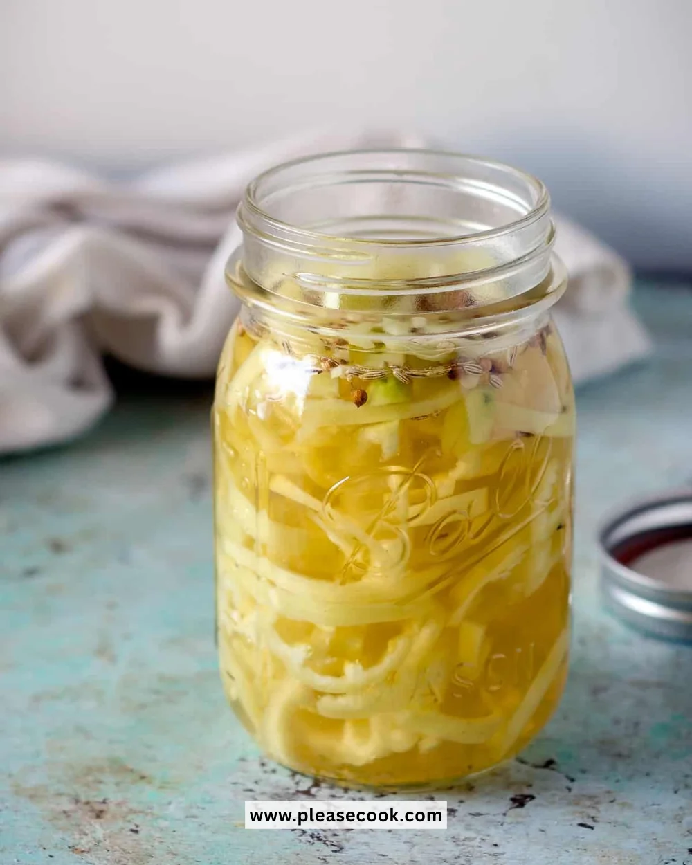 Homemade pickled banana peppers in a jar with spices.