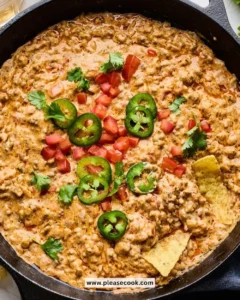 Rotel Dip with Ground Beef served in a bowl, topped with fresh herbs.
