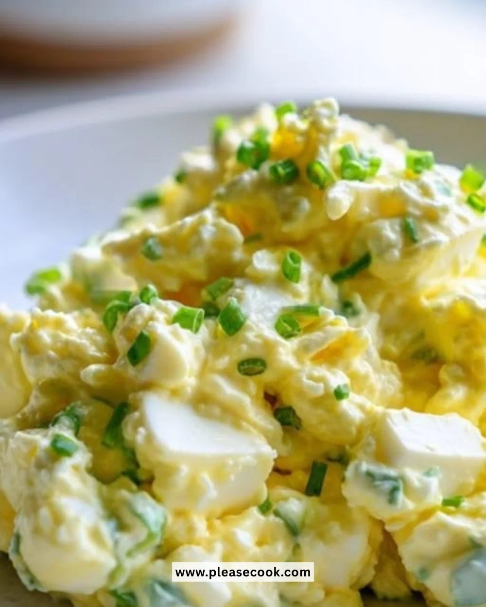 Bowl of ultimate creamy egg salad garnished with herbs