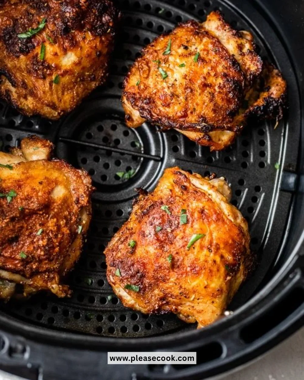 Crispy air fryer chicken thighs garnished with herbs on a plate