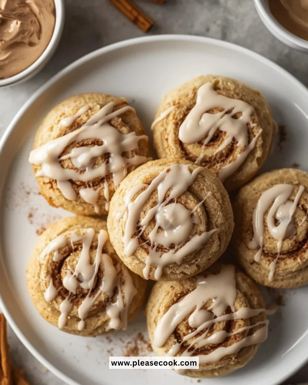 No-bake cinnamon roll cookies stacked on a plate with frosting