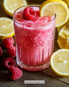 Refreshing raspberry lemonade slushie in a chilled glass with a lemon slice