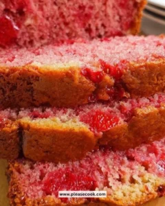 Loaf of homemade strawberry banana bread with slices on a wooden table.