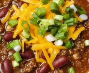 Delicious bowl of hearty chili topped with cheese and green onions.