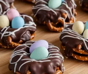 Chocolate-covered pretzel nests decorated with colorful sprinkles on a plate