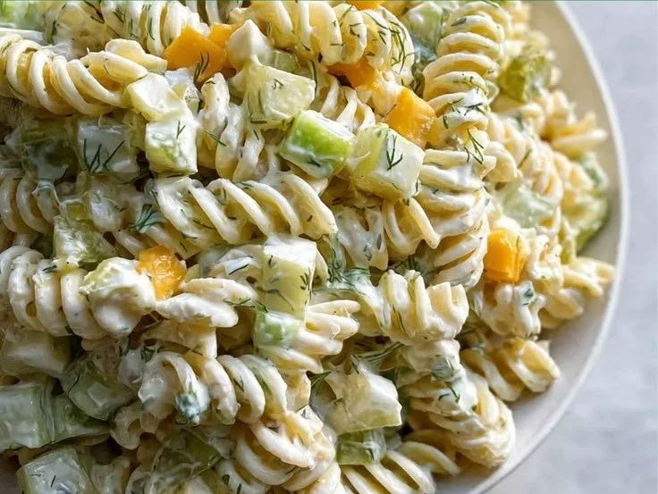 Creamy dill pickle pasta salad served in a bowl with fresh herbs